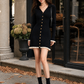 Woman wearing a black ribbed knit mini sweater dress with cream trim